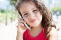 Cute child in a red shirt listening at mobile phone outside Royalty Free Stock Photo