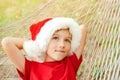 Cute child in santa hat and resting on hammock. Little boy dreaming about christmas gifts. Christmas family vacation at tropical Royalty Free Stock Photo