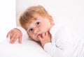 Cute child - shy girl lying on white sofa sucking thumb or finger Royalty Free Stock Photo