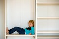 Cute child, sit in a white box in open wardrope Royalty Free Stock Photo