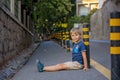 Cute child, sitting on the ground in the city, playing with little pet maltese dog Royalty Free Stock Photo