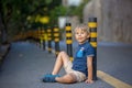 Cute child, sitting on the ground in the city, playing with little pet maltese dog Royalty Free Stock Photo