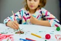 Cute child sitting at the table and drawing red heart on white paper Royalty Free Stock Photo