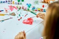 Cute child sitting at the table and drawing red heart on white paper Royalty Free Stock Photo