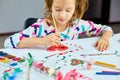 Cute child sitting at the table and drawing red heart on white paper Royalty Free Stock Photo