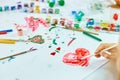 Cute child sitting at the table and drawing red heart on white paper Royalty Free Stock Photo