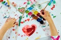 Cute child sitting at the table and drawing red heart on white paper Royalty Free Stock Photo