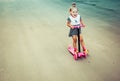 Cute child skilfully skates on a pink two-wheeled scooter on a s Royalty Free Stock Photo