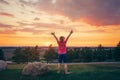 Cute child standing with her arms raised on hill outdoor at sunset.  Girl kid having fun outdoors enjoying life at sunrise. Local Royalty Free Stock Photo