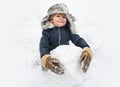 Cute child standing in winter hat with red nose. Joyful kid Having Fun and making snowman in Winter Park. Winter clothes