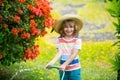 Cute child in straw hat is laughing with water spraying hose. Royalty Free Stock Photo