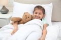 Cute child with stuffed bunny resting in bed