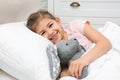 Cute child with stuffed rabbit resting in bed