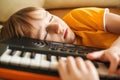 Cute child tired of learning to play the synthesizer