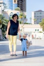 Cute child, toddler boy and grandmother,  walking hand in hand in the city, baby holding teddy bear, smiling Royalty Free Stock Photo