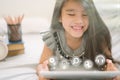 Cute child using a tablet and smiling while sitting on sofa at home