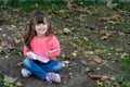 Cute child writing in notebook using pen and smiling. Four years old kid sitting on grass