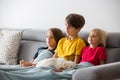 Cute children, brothers watching TV with little puppy dog, lying on the sofa with soft blanket Royalty Free Stock Photo