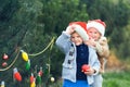 Cute children decorate Christmas trees in garland and balls decorated backyard