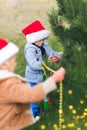 Cute children decorate Christmas trees in garland and balls decorated backyard