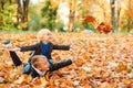 Cute children playing and laughing on autumn walk. Happy brothers throwing autumn leaves outdoors