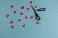 Cute children\'s work, hearts unevenly cut from red colored paper, small office scissors nearby.