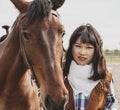Cute chinese cowgirl while taking care of her horse Royalty Free Stock Photo