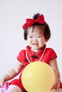 Cute Chinese little baby in red cheongsam play yellow balloon