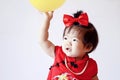 Cute Chinese little baby in red cheongsam play yellow balloon