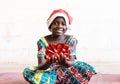 Cute Christmas African Black Girl with Funny Hat and Red Present at Home in Bamako, Mali Royalty Free Stock Photo