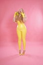 Cute chubby blonde girl posing in yellow latex rubber clothes with sweet bananas
