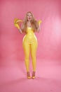 Cute chubby blonde girl posing in yellow latex rubber clothes with sweet bananas