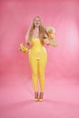 Cute chubby blonde girl posing in yellow latex rubber clothes with sweet bananas