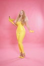 Cute chubby blonde girl posing in yellow latex rubber clothes with sweet bananas