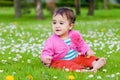 Cute chubby toddler sitting on the grass smiling exploring nature outdoors in the park Royalty Free Stock Photo