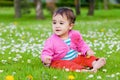 Cute chubby toddler sitting on the grass smiling exploring nature outdoors in the park