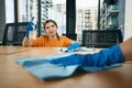 Cute cleaning company employees in rubber protective gloves disinfect desktops