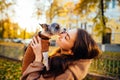 Cute closeup photo of a dog-owner holding her cute pet, funny york terrier is licking its owner. A woman is standing on a city