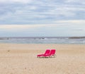 Cute and colorful pink beach chairs on the beach.