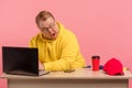 Cute comic man in bright casual wear working on computer with funny face Royalty Free Stock Photo