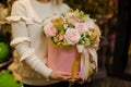 Cute composition of fresh pink flowers in round box in hands of woman.