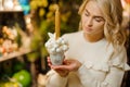 Cute composition in pot of white Christmas balls and golden candle in hands of woman Royalty Free Stock Photo