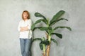 Cute confident mature woman standing with green plant