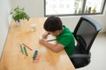 Cute confused smiling boy doing homework, coloring pages, writing and painting . Children paint. Kids draw. Preschooler with books