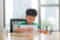 Cute confused smiling boy doing homework, coloring pages, writing and painting . Children paint. Kids draw. Preschooler with books Royalty Free Stock Photo
