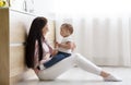 Young mother embracing with her baby on kitchen floor Royalty Free Stock Photo