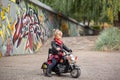 Cute cool child girl in leather jacket riding the motorbike in summer park Royalty Free Stock Photo