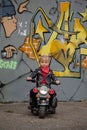 Cute cool child girl in leather jacket riding the motorbike in summer park Royalty Free Stock Photo