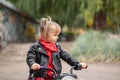 Cute cool child girl in leather jacket riding the motorbike in summer park