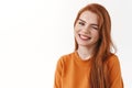 Cute and coquettish silly redhead woman with long ginger hair, winking excited, smiling from overjoy and enthusiastic